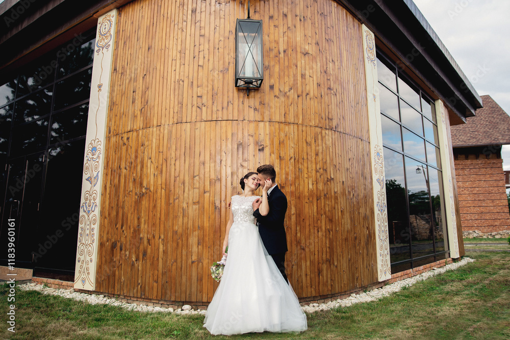 A bride and groom are standing in front of a building, with the bride holding a bouquet A bride and groom are standing in front of a building, with the bride holding a bouquet