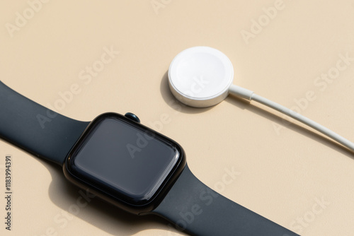 A stylish smartwatch resting on a table with its magnetic charging dock, representing convenience and modern technology. photo