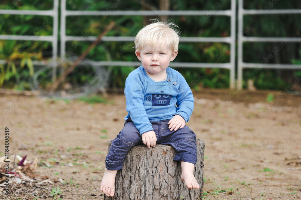 Portrait of little toddler boy sitting in garden with relaxed expression Portrait of little toddler boy sitting in garden with relaxed expression