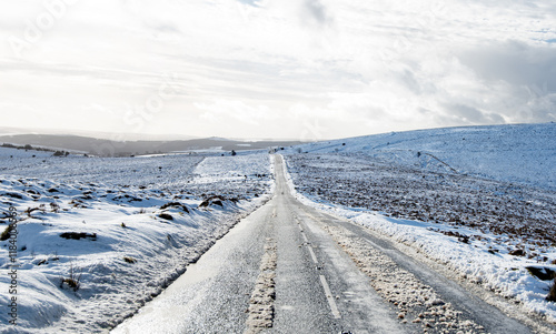 Dartmoor in the snow with a road cutting across Dartmoor national park in winter. Hazardous driving conditions. Beautiful white landscape photo