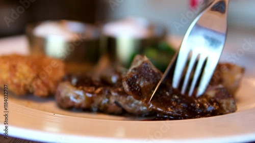 Chef slicing freshly grilled juicy beef steak meat with a knife on a wooden cutting board in the kitchen, food close-up zoom in