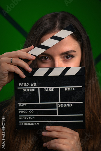 Young woman with black filmmaker clapper board on green background