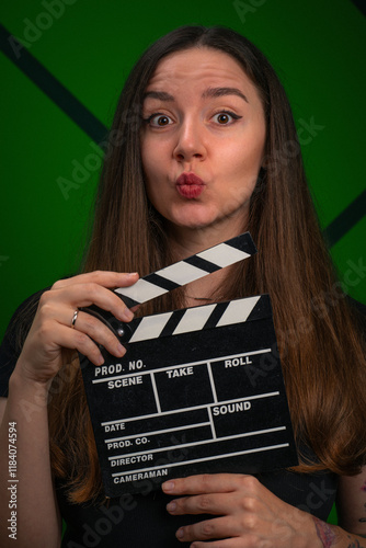 Young woman with black filmmaker clapper board on green background