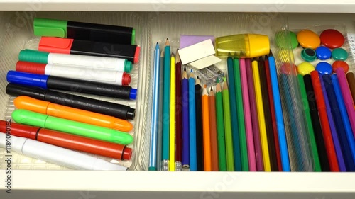 Stationery and office supplies are laid out in an open drawer of a white desk. Organizing and storing things in the house