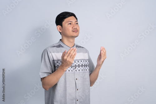 Muslim man praying for Ramadan with calm expression on isolated white background
