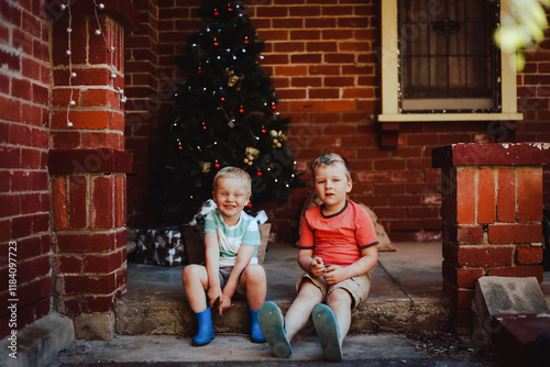 Little boys sitting together in front of Christmas tree photo