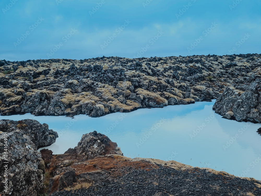Obraz premium A stunning view of the Blue Lagoon in Iceland, showcasing its iconic milky blue geothermal waters surrounded by rugged volcanic rocks. The misty atmosphere 