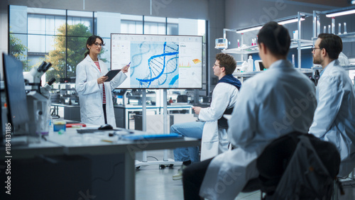 Group of Talented Female and Male STEM Students Having a Meeting with Their Project Leader in a Modern Laboratory. Young Female Specialist Showing a Presentation About Biochemistry on Screen