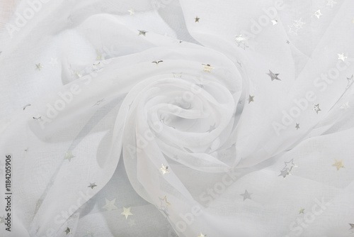 The white fabric is curled in waves into a rose. Tulle pleats with silver stars.