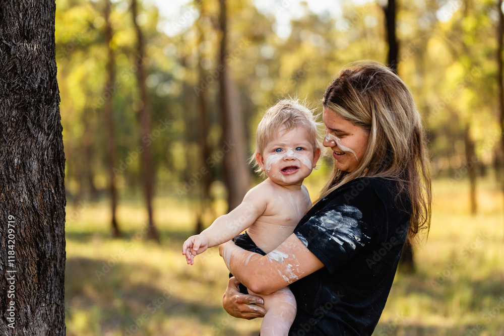 Aboriginal mum cuddling baby boy in Australian bushland painted with traditional ochre Aboriginal mum cuddling baby boy in Australian bushland painted with traditional ochre