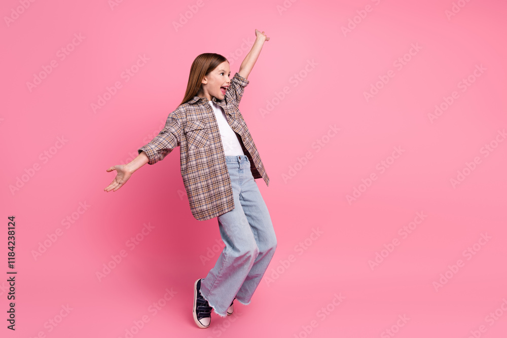 Young cheerful girl in trendy plaid shirt posing against a pink background with outstretched arms. Young cheerful girl in trendy plaid shirt posing against a pink background with outstretched arms.