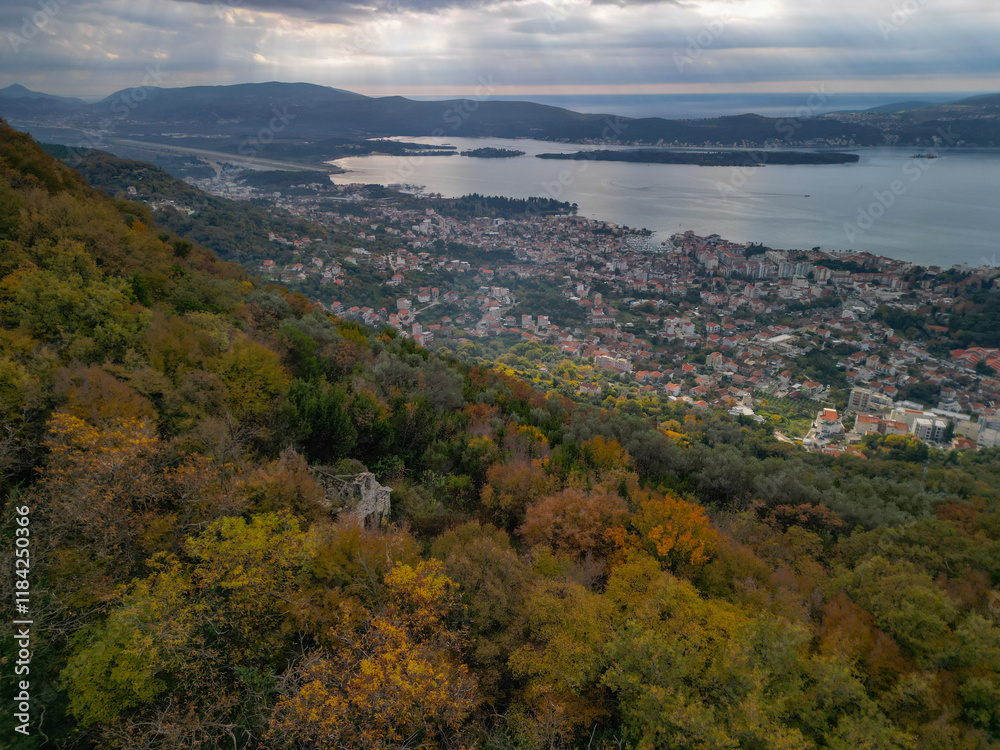 Fototapeta premium Aerial view of abandoned ancient stone church ruins hidden in autumn forest on a mountain slope above Tivat, Montenegro 