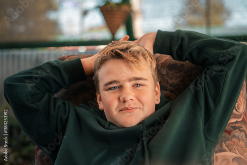 Portrait of teenage boy relaxing on outdoor chair photo