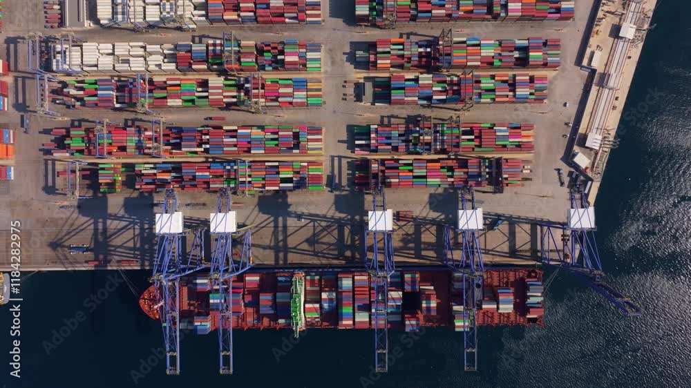 Aerial view of a busy container port with stacked shipping containers and cranes by the water, Perama, Greece. Aerial view of a busy container port with stacked shipping containers and cranes by the water, Perama, Greece.