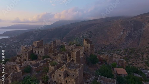 Aerial view of an abandoned village at sunset with serene ruins and picturesque hills, Vathia, Greece. photo