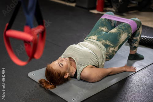 Woman performing glute bridge exercise with resistance band in gym photo