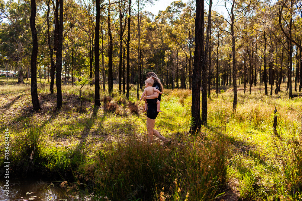 Aboriginal woman with her eight month old baby boy walking together through Australian bushland Aboriginal woman with her eight month old baby boy walking together through Australian bushland