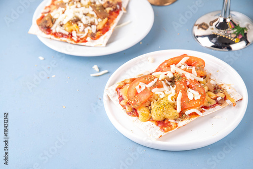 Matzah Pizza on light blue background with ingredients, cheese, tomato sauce. Food ideas and recipe for Jewish Pesach and Passover holidays photo