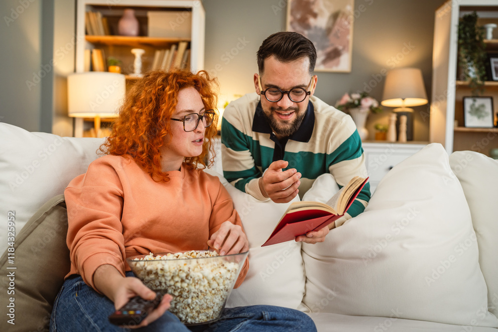 cheerful couple enjoy together on sofa with book and popcorn cheerful couple enjoy together on sofa with book and popcorn
