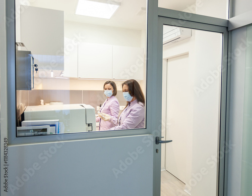 Two dentists working with autoclave sterilizer in dental clinic photo