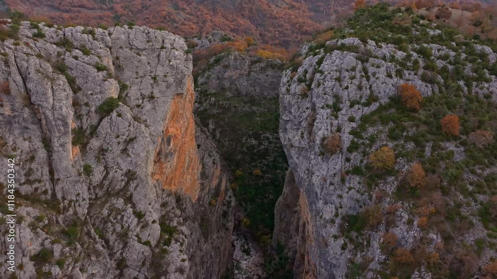 Aerial view of Portitsa ancient stone bridge over a winding river in a dramatic gorge surrounded by rugged cliffs and autumn foliage, Spileo, Greece. Aerial view of Portitsa ancient stone bridge over a winding river in a dramatic gorge surrounded by rugged cliffs and autumn foliage, Spileo, Greece.