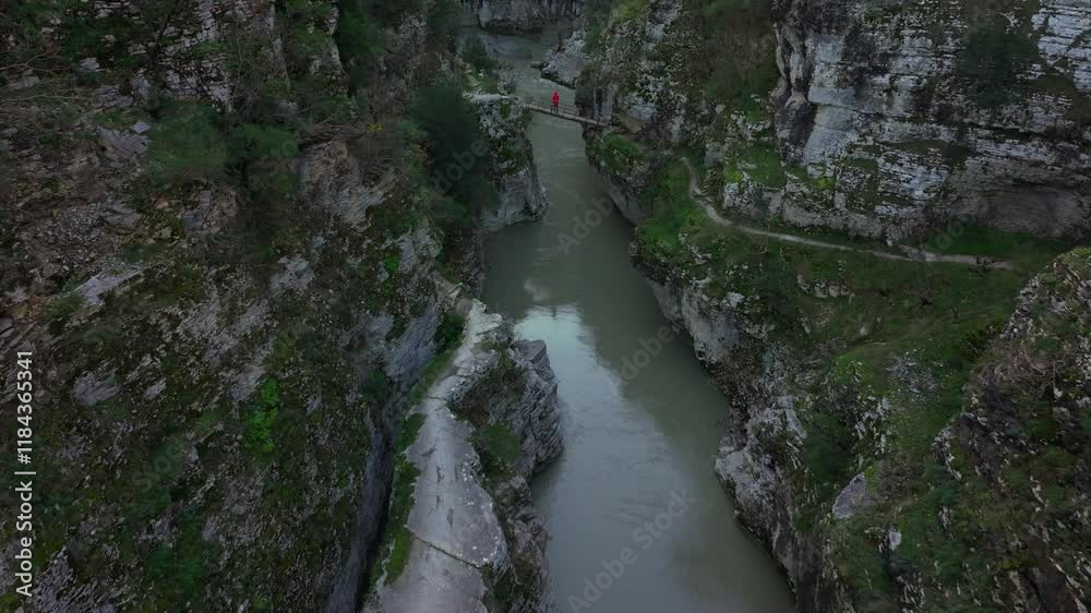 Aerial view of osumi canyon with osum river and bridge surrounded by rugged cliffs and greenery, Skrapar, Albania.