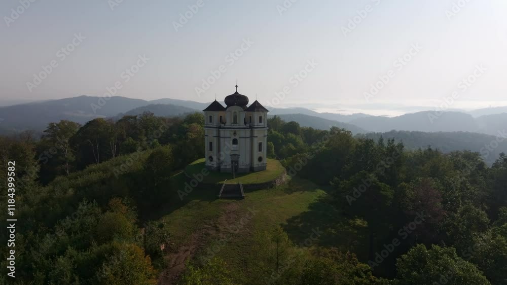 Aerial view of the historic Kostel sv. Jana Krtitele a Panny Marie Karmelske church surrounded by tranquil forests and hills, Smolotely, Czech Republic.
