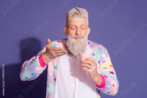 Trendy man in unicorn pajama enjoying a morning coffee against a vibrant purple background photo