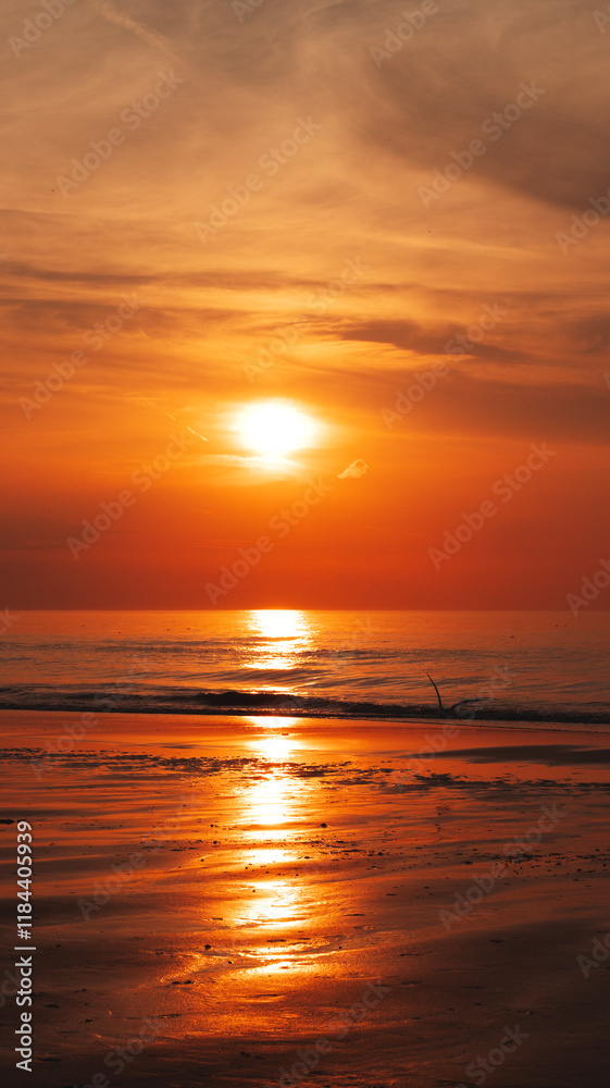 Obraz premium Magnificent sunset over the sea, casting warm colors across the sky and reflecting on the calm waters.