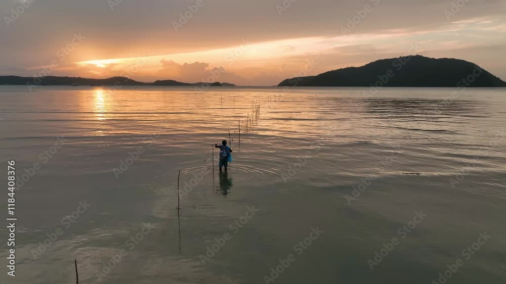 Aerial view of tranquil ocean waves at sunset with a silhouette of a fisherman, Phuket, Thailand. Aerial view of tranquil ocean waves at sunset with a silhouette of a fisherman, Phuket, Thailand.