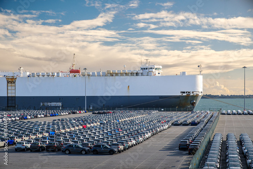 Obraz na płótnie Large cargo ship docked near a vast parking lot of vehicles w salonie