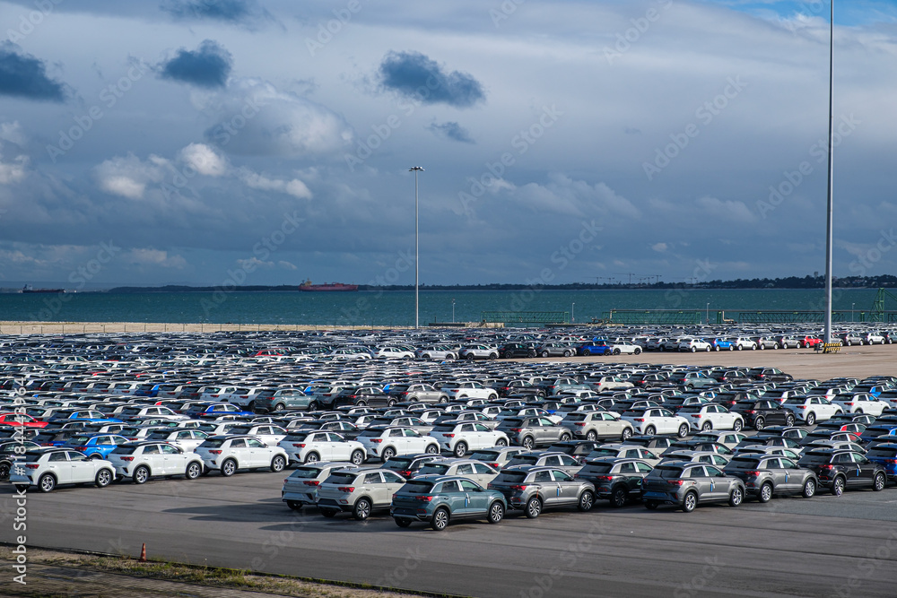 Large parking lot filled with new vehicles near the waterfront