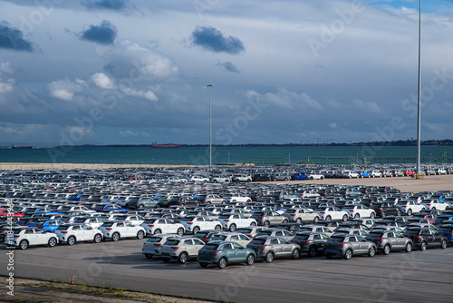 Large parking lot filled with new vehicles near the waterfront