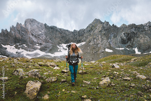 Woman climbing mountains with trekking poles and backpack gear travel adventure lifestyle hiking solo female traveler exploring wild nature trails, active vacations outdoor extreme tour photo