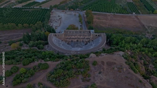 Aerial view of ancient Aspendos Theatre at sunset surrounded by scenic fields and trees, Serik, Turkey. photo