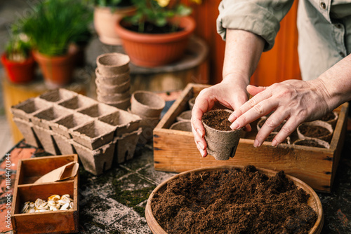Gardener putting soil and compost into biodegradable peat pots. Planting and sowing at springtime