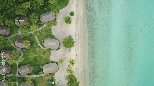 Top down view bungalows huts lining white sand beach, crystal clear turquoise water. Tropical island luxury eco hotel accommodation in palm trees forest park. Remote wild nature, exotic summer travel