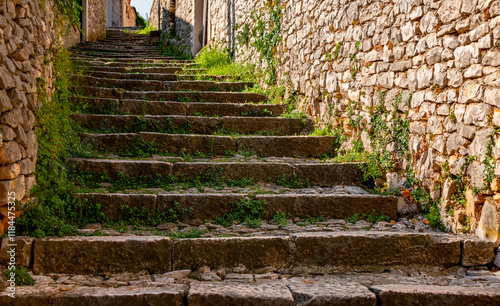 Historic stone staircase made of limestone in a small Croatian village on the island of Brac in the Adriatic Sea. Weeds grow in the joints. Idyllic ascent in an alley in mediterranean Pučišća. photo