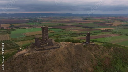 Aerial view of hazmburk castle ruins on a hilltop surrounded by scenic fields and cloudy sky, Klapy, Czech Republic. photo