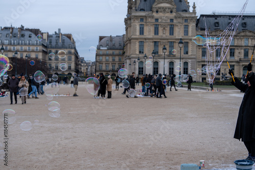 Fototapeta Naklejka Na Ścianę i Meble -  People enjoy whimsical bubble display at an outdoor park in Paris during a chilly afternoon