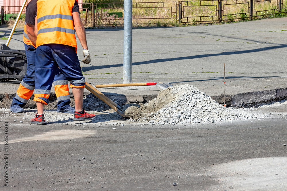 Workers skillfully repair a city street with fresh concrete on a sunny day. Copy space.