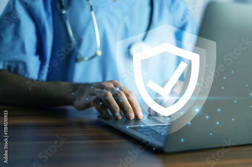Obraz na płótnie Doctor typing on a laptop with a glowing shield icon, symbolizing cybersecurity and data protection in healthcare. w salonie