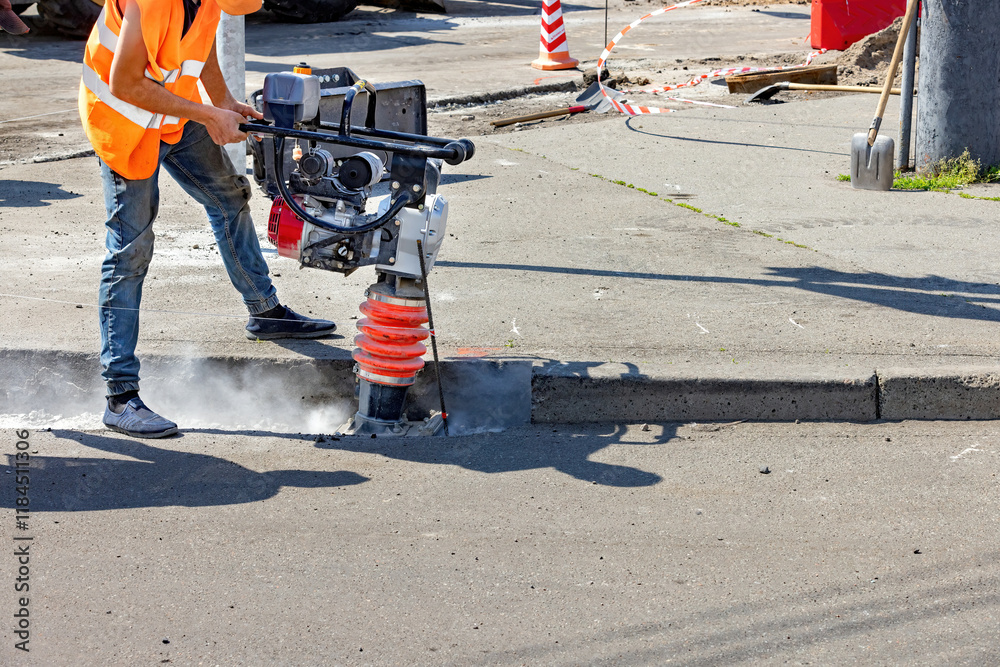 Construction worker using equipment to break concrete on a sunny day. Copy space.