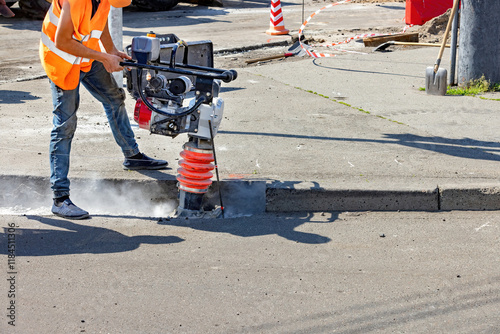 Obraz na płótnie Construction worker using equipment to break concrete on a sunny day. Copy space. w salonie