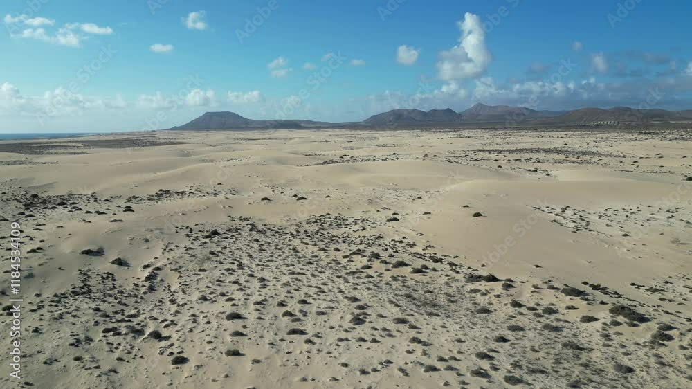 Aerial view of beautiful arid desert dunes under a clear sky with mountains in the background, Canary Islands, Spain. Aerial view of beautiful arid desert dunes under a clear sky with mountains in the background, Canary Islands, Spain.