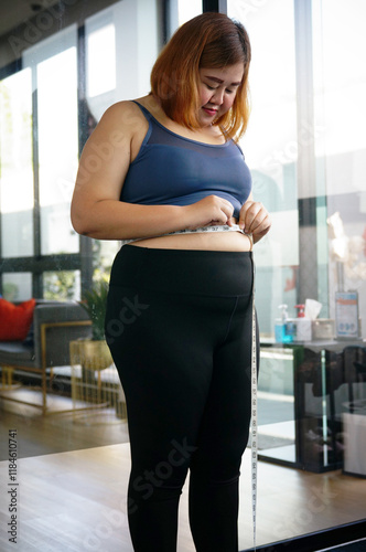 Obese woman with fat belly in dieting concept. Overweight woman touching his fat belly and want to lose weight. Fat woman her waist with a centimeter. Shape up healthy stomach muscle and diet