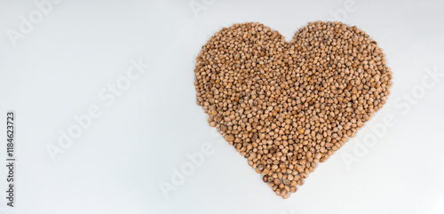 A heart shape made of cherry kernels is arranged on a clean white background. The smooth, natural kernels have visible textures and earthy tones. The simple composition highlights the kernel details