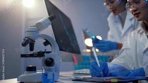 Two female scientists discussing test results displayed on a computer screen in a modern laboratory