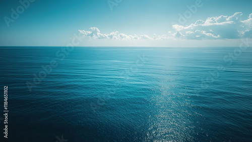 Endless ocean view under bright blue sky with gentle waves and distant horizon clouds