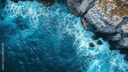 Drone view of rocky coastline with crashing ocean waves, vibrant blue water and natural serenity.